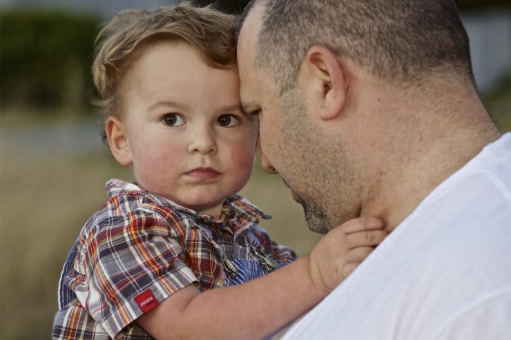 A man holding his son in the arms of him.