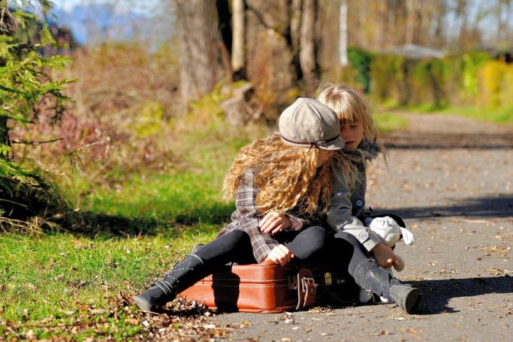 Two girls sitting on the ground in a park.