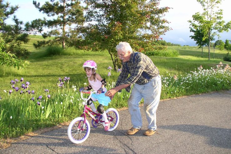 A man helping a little girl on her bike