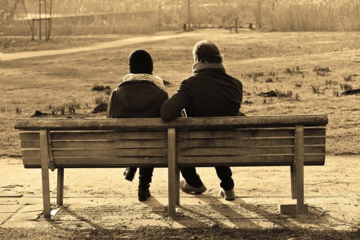 Two people sitting on a bench in the park