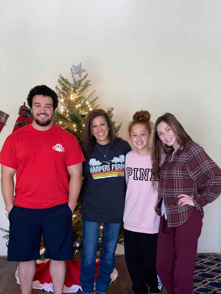 A group of people standing in front of a christmas tree.